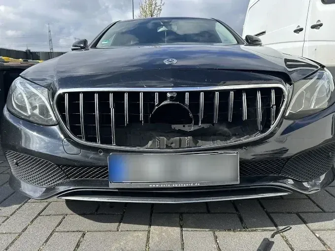 Dunkelgraue Mercedes E-Klasse mit eingedrücktem Kühlergrill und beschädigter Frontschürze nach einem Auffahrunfall, aufgenommen bei der Schadenaufnahme